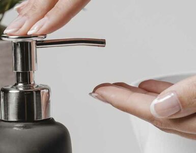 Mujer poniendo jabón en sus manos con la ayuda de un dispensador d jabón.
