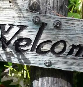 Letrero de madera entre plantas con la palabra "Welcome".