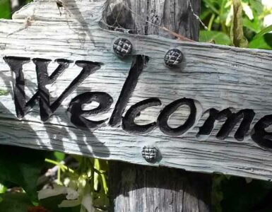 Letrero de madera entre plantas con la palabra "Welcome".